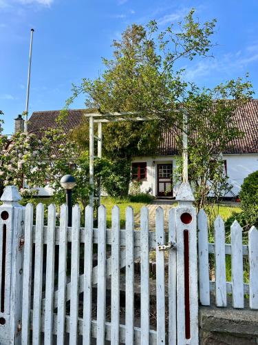 a white picket fence in front of a house at Noorbohandelens Bed & Breakfast in Stege