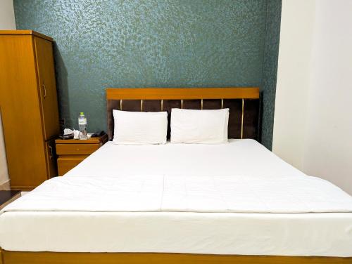a bed with white sheets and a wooden headboard at Hotel StayInn - Airport Branch Karachi in Karachi