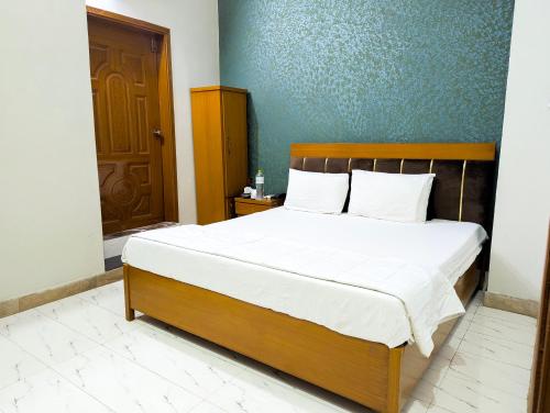 a bedroom with a large bed with a wooden headboard at Hotel StayInn - Airport Branch Karachi in Karachi
