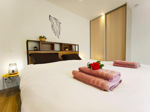 une chambre avec un grand lit blanc avec deux serviettes dans l'établissement Oasis romantique - Sauna, à Peyruis