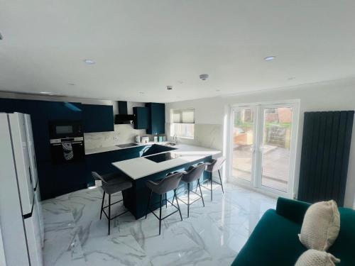 a kitchen with a sink and a counter with chairs at Anjaneya Homes - Double Room En-suites with Kitchenette in Ashford