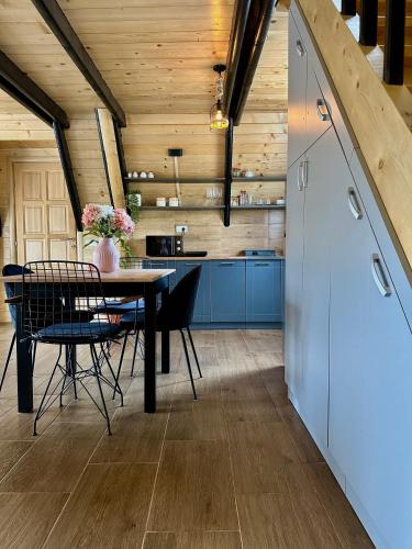 a kitchen and dining room with a table and blue cabinets at Planinska Brvnara Zlatni Bor in Nedići