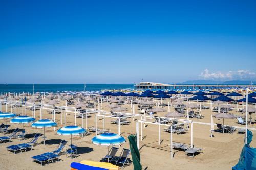 a beach filled with blue and white chairs and umbrellas at Appartamento Luxury vista mare in Lido di Camaiore