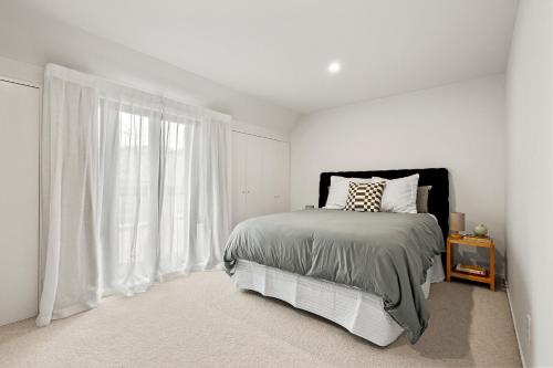 a bedroom with a bed and a large window at Harakeke Whāre - Christchurch Holiday Homes in Christchurch
