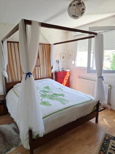 une chambre avec un lit à baldaquin avec des rideaux blancs dans l'établissement MARCHE DE Noel STRASBOURG, à Illkirch-Graffenstaden