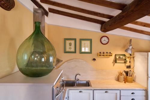 Una cocina con un gran jarrón verde en la pared. en la Soffitta, en Campiglia Marittima