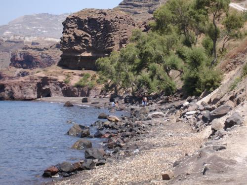 a group of people standing on a rocky beach near the water at Paradise Resort in Akrotiri
