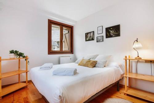 a bedroom with a large white bed with a window at Cantal by Cardi Suites in Sallent de Gállego