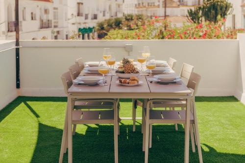 a wooden table with a plate of food and glasses of wine at GAIA Beach House - Exclusive Stay & Free Parking in Conil de la Frontera