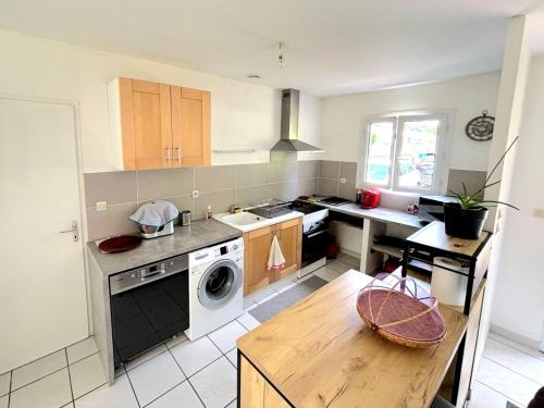 une cuisine avec un évier et une cuisinière four supérieur dans l'établissement Maison vacances et cure thermale, à Vergeroux