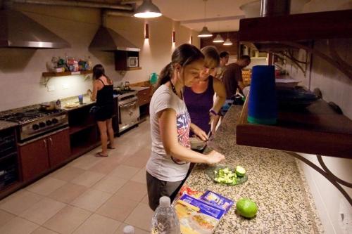 a woman standing in a kitchen preparing food at El Gualicho Hostel in Puerto Madryn
