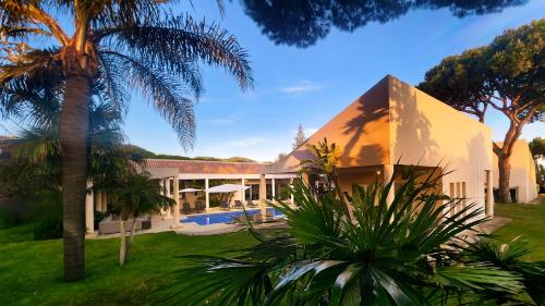 an exterior view of a house with a palm tree at Seventies - Private Pool - 16 Guests - Quarteira in Quarteira
