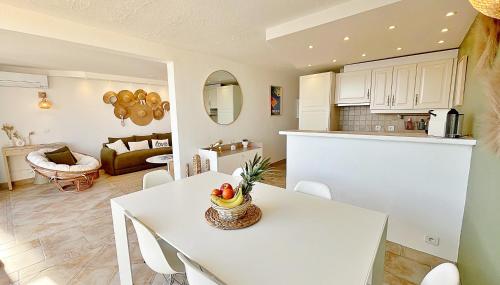 une cuisine et un salon avec une table et des chaises blanches dans l'établissement Superb T3 with terrace and sea view, à Théoule-sur-Mer