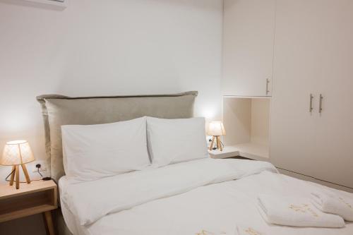 a bedroom with a bed with white sheets and two lamps at Amar V in Lechaio