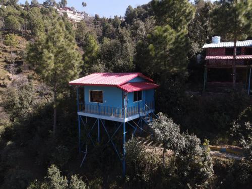 a blue house with a red roof in a forest at Shaantvan Homestay-Near Bhalughar Waterfall-Mukteshwar in Mukteswar