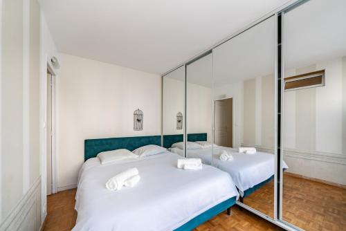 une chambre avec deux lits et un miroir dans l'établissement 3 pièces centre-ville Cannes - Croisette - Climatisation séjour, à Cannes
