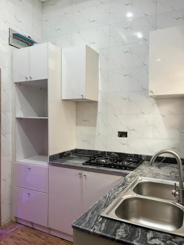 Una cocina con gabinetes blancos y un fregadero. en Modern Apartment in Ikeja, Lagos, en Iseri