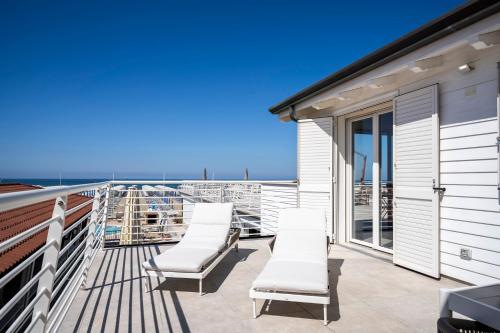a balcony with white chairs and a view of the ocean at Appartamento Luxury vista mare in Lido di Camaiore