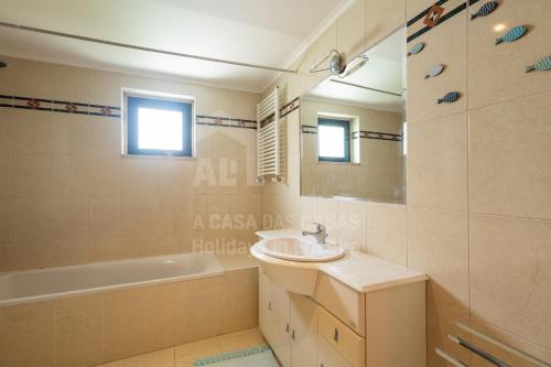 Un baño con lavabo, bañera y espejo. en Infinity Waves by ACasadasCasas, en Ericeira