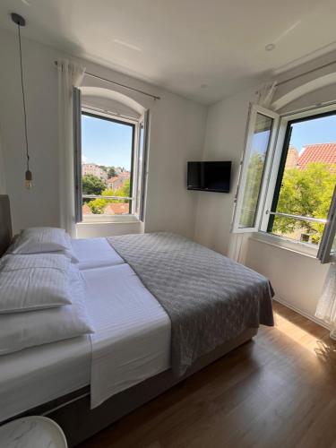 a bedroom with a large bed and two windows at Soukki Town Centre Suites 2 in Split
