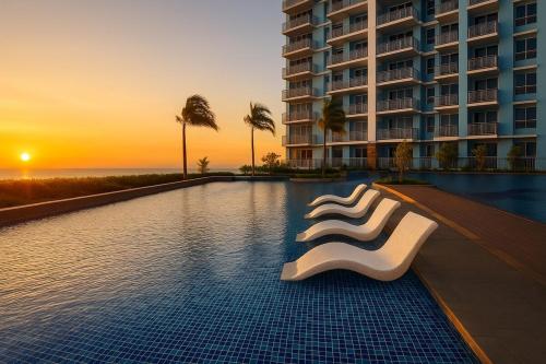 a hotel swimming pool with a white chair in front of a building at Cozy 1BR near Solaire, Okada, Mall of Asia in Manila