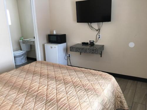 1 dormitorio con 1 cama y TV en la pared en Ace Budget Motel, en San Diego