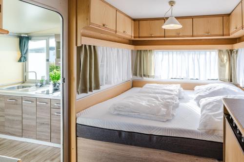 a bed in the middle of a small room at TiBu - Mietwohnwagen Fehmarn in Fehmarn