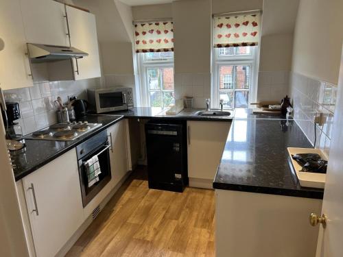 a large kitchen with black counter tops and appliances at The Talbot and apartment in Iwerne Minster