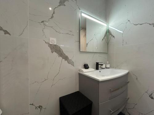 une salle de bain blanche avec un lavabo et un miroir dans l'établissement 1 Clairmarais T2 cosy a 2 pas du centre-ville, à Reims