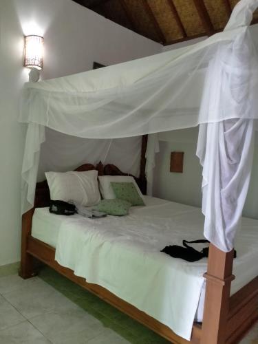a bedroom with a white bed with a canopy at Exotic house in Gili Meno
