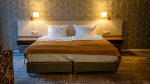 a large bed in a hotel room with two lamps at Heide Hotel Reinstorf in Reinstorf