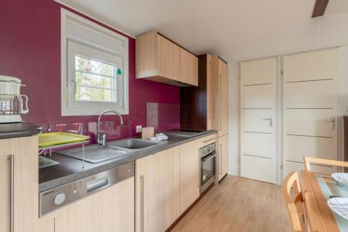 a kitchen with red walls and wooden cabinets at Bois d'amour - Piscine - Terrasse in Dinard