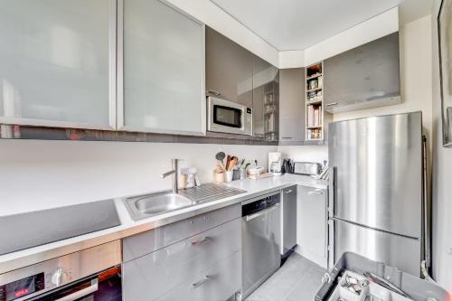 une cuisine avec des armoires blanches et un réfrigérateur en acier inoxydable dans l'établissement Lecourbe - Wifi - 15ème arrondissement, à Paris