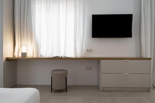 a bedroom with a desk with a tv and a window at enδόtera chios apartments in Chios