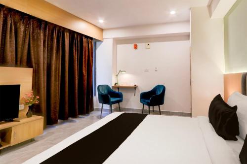 a bedroom with a bed and two chairs and a desk at Super Townhouse Lotus Grand in Hyderabad