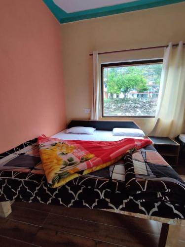 a bed sitting in a room with a window at Shiva heights Trek and stay in Chopta