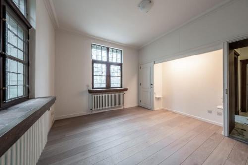 an empty room with a wooden floor and windows at Luxury Villa Schaffen with a private gym in Diest