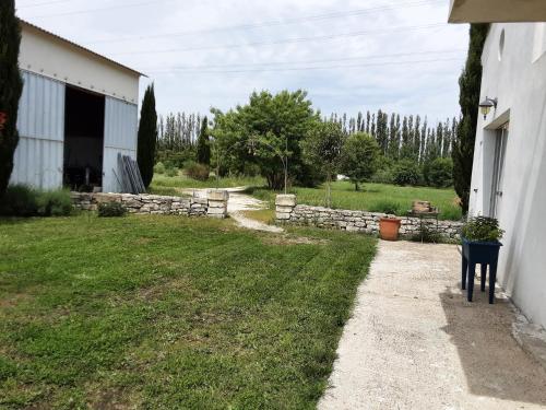 une cour à côté d'un bâtiment avec un mur en pierre dans l'établissement M'as de l espine, à Eygalières
