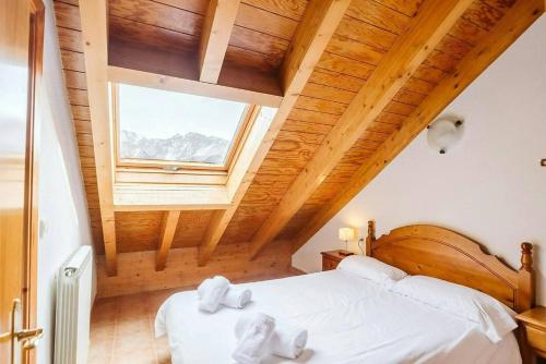 a bedroom with a bed with white sheets and a window at Olympia by Cardi Suites in Formigal