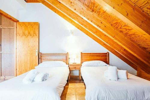 two beds in a room with wooden ceilings at Olympia by Cardi Suites in Formigal
