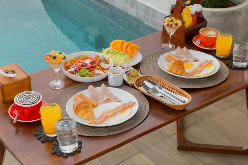 Tasana bar and luxury resort في كو لان: طاولة مع أطباق من الطعام وعصير البرتقال