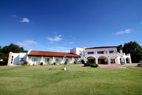 a large white building with a grass field in front at La Campiña Club Hotel & Spa in Santa Rosa