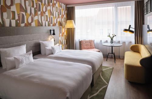 a hotel room with two beds and a chair at NYX Hotel Berlin Köpenick by Leonardo Hotels in Berlin