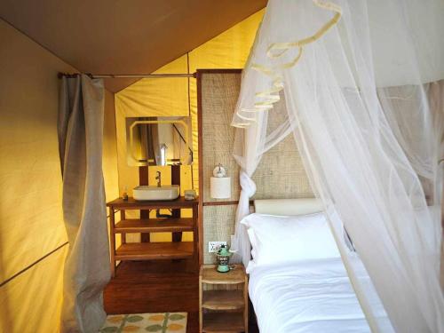 a bedroom with a canopy bed and a sink at Longoza Ecolodge in Andasibe