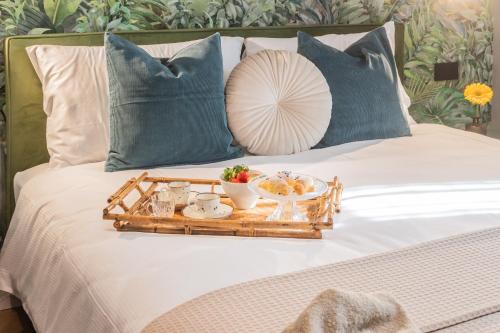 a tray with food on a bed with blue pillows at Rezia Apartments by Rent All Como in Como