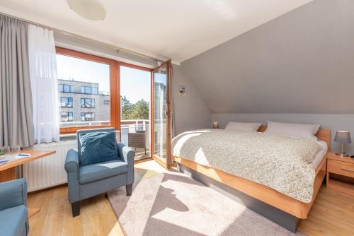 a bedroom with a bed and a chair and a window at Hotel Villa Sonneck-Adults Only in Sankt Peter-Ording