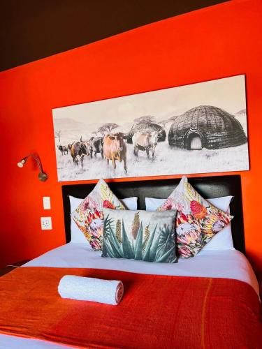 a bedroom with a bed with an orange wall at Nogixa Lodge in Umzimkulu