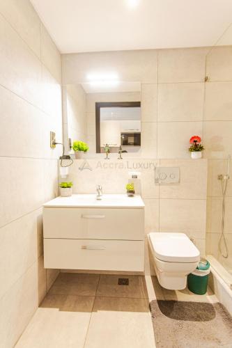 a bathroom with a white sink and a toilet at Accra Luxury Apartments @ The Signature in Accra