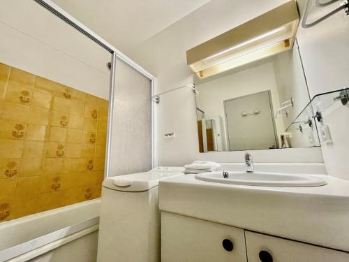 une salle de bain blanche avec un lavabo et un miroir dans l'établissement Appart T3 - 200 m plage - Dernier étage vue mer et camargue, à La Grande Motte