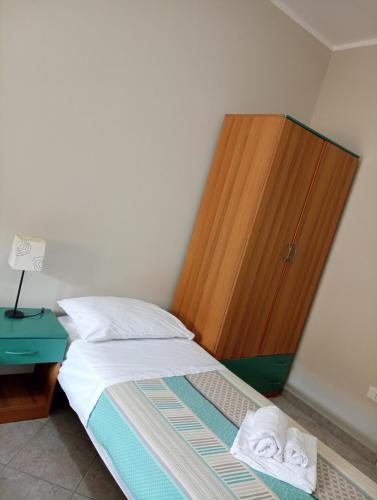a bedroom with a bed and a wooden cabinet at Aurora and Brothers' home in Falerna Marina
